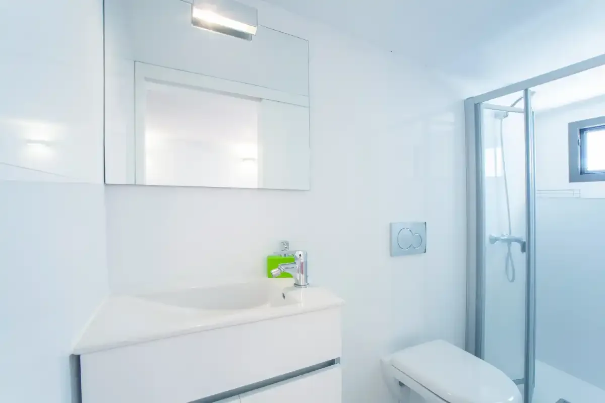 A bright bathroom with a sink, mirror, and glass-enclosed shower.