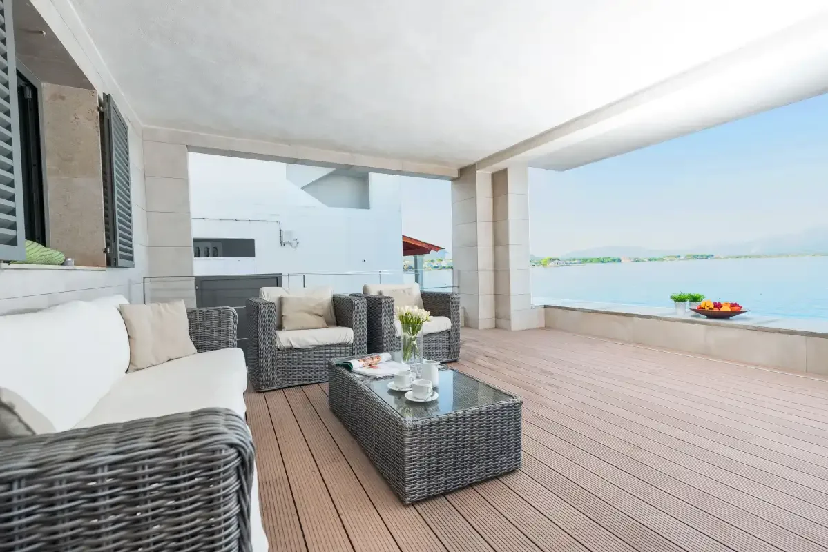 A covered outdoor seating area opens onto a terrace overlooking the water.
