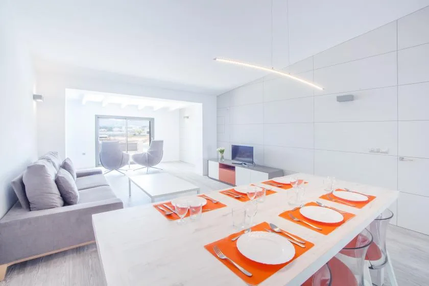 A bright modern dining area with a long table set with orange placemats.