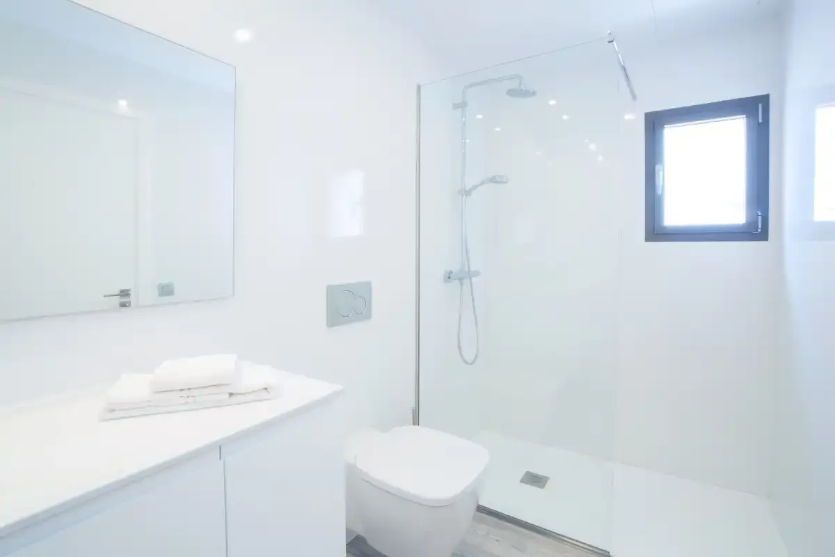 A bright bathroom with a shower, toilet, and sink.