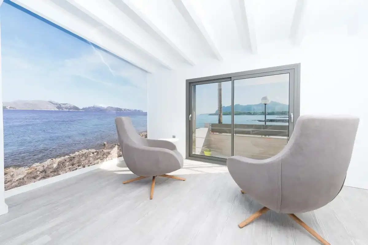 A bright living area with two chairs beside large windows overlooking the sea.