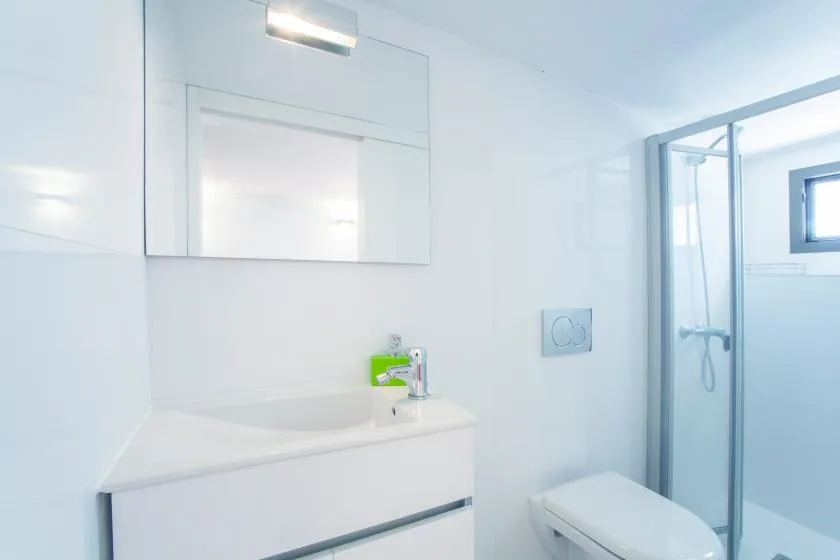 A bright bathroom with a sink, mirror, and shower.