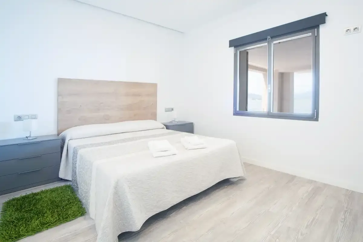 A bright bedroom with a neatly made bed and a window.