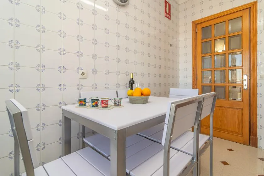 A tiled dining area with a table, seating, and a wooden glass-paneled door.