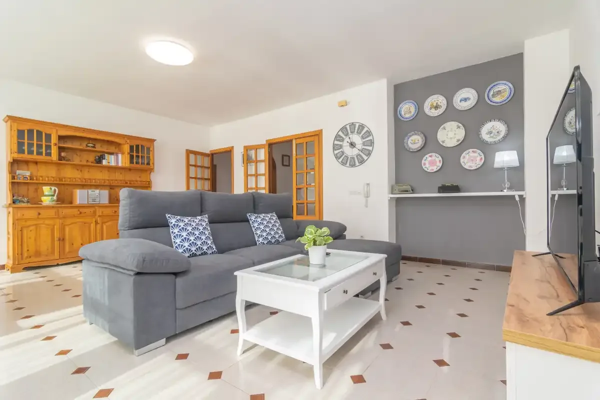 A living room with gray seating, a white coffee table, and wooden cabinetry.