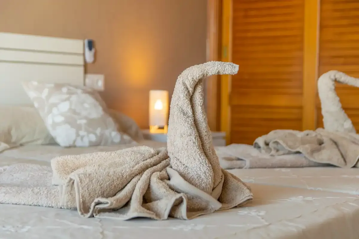 A bedroom with folded towels arranged on the bed.