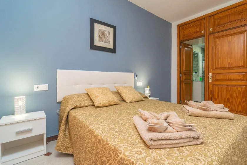 A bedroom with a double bed, bedside tables, and wooden wardrobes.