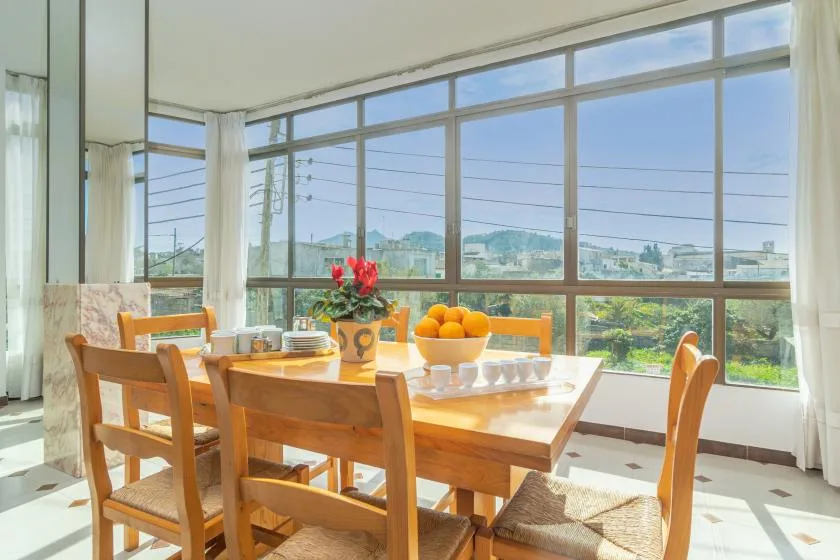 A dining area with a wooden table set beside large windows.