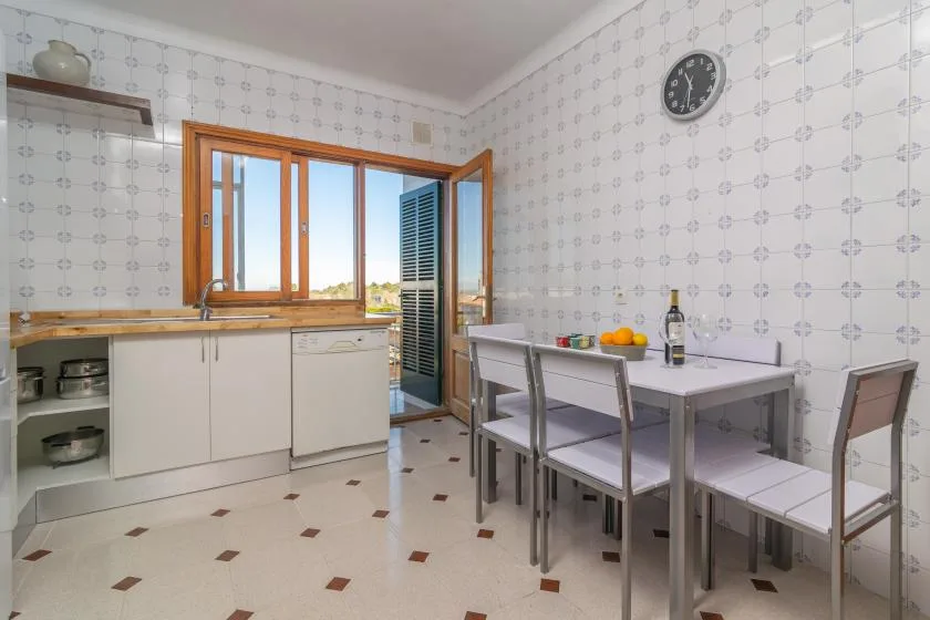 A tiled kitchen and dining area with a table beside an open window.