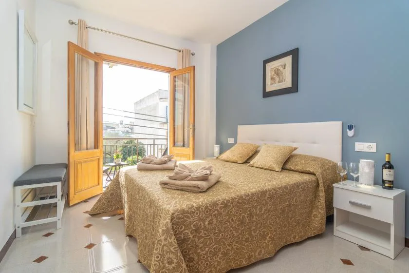 A bedroom with a double bed and open wooden doors leading to a balcony.