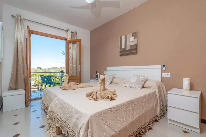 A bedroom with a large bed, light bedding, and an open balcony door.