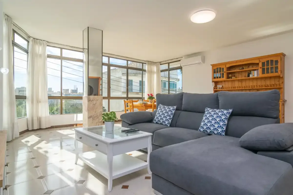 A bright living room has a gray sectional sofa beside large windows.