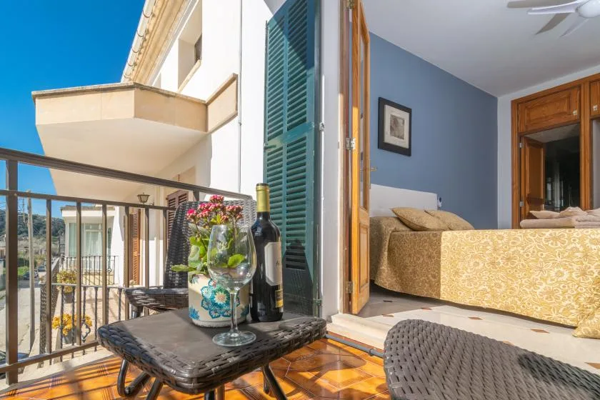 A bedroom opens onto a balcony with a small table and flowers.