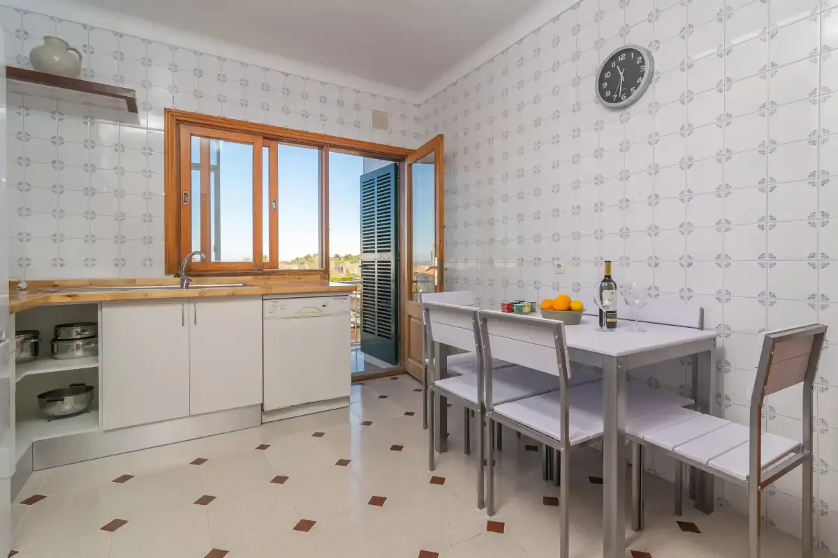 A tiled kitchen and dining area with a table beside the open window.
