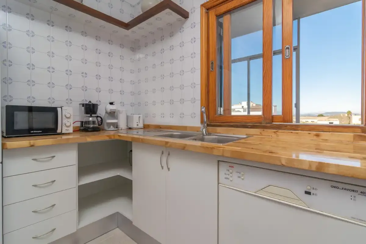 A bright kitchen with wooden countertops and a large window.