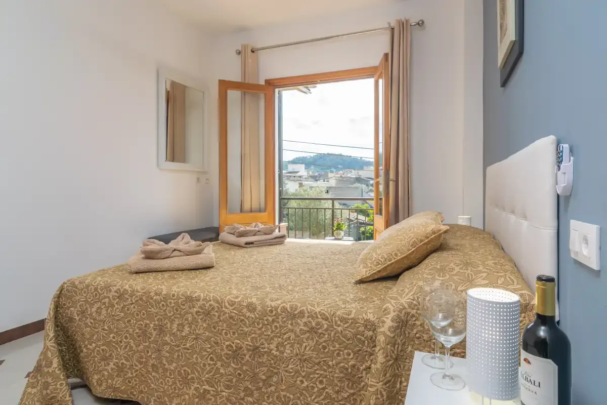 A bedroom with a patterned bedspread and an open window overlooking the hills.
