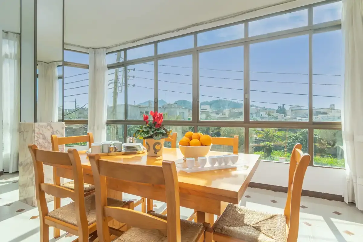 A bright dining area with a wooden table beside large windows.