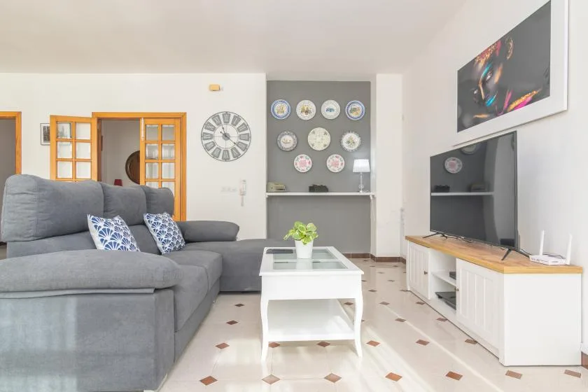 A living room with gray seating, a white coffee table, and a television.