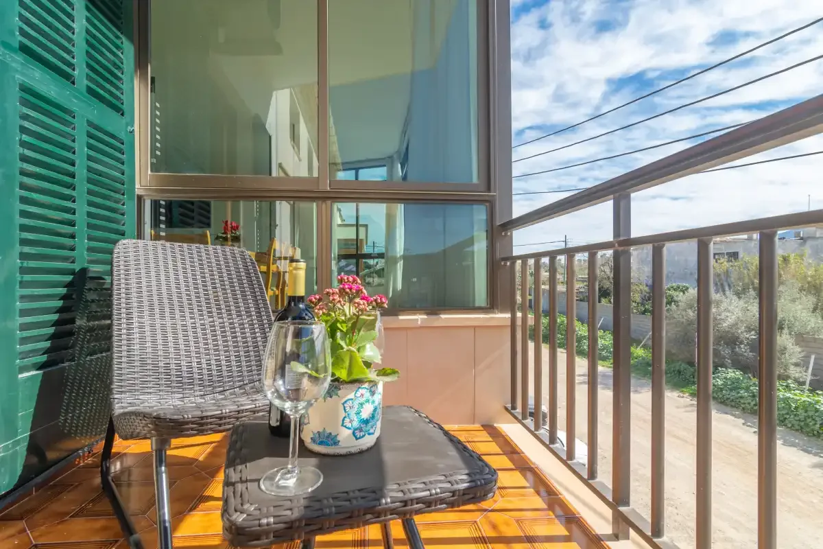 A narrow balcony with outdoor seating and a glass railing.