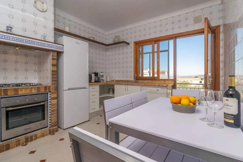 A tiled kitchen with a dining table set by an open window.