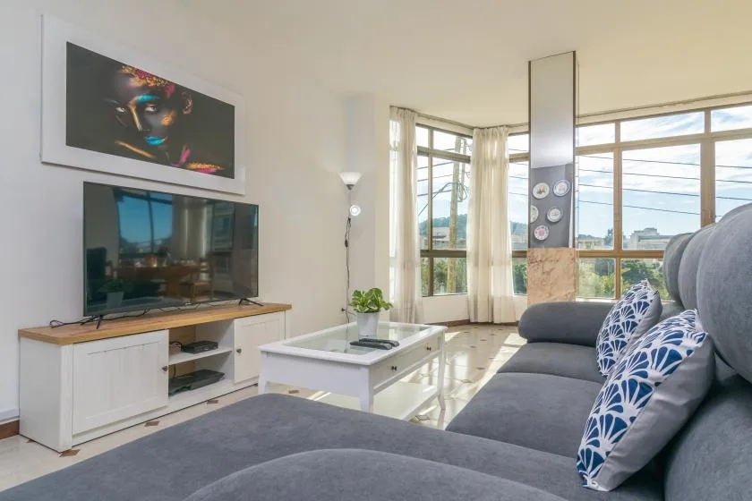A bright living room with a sectional sofa, coffee table, and wide windows.
