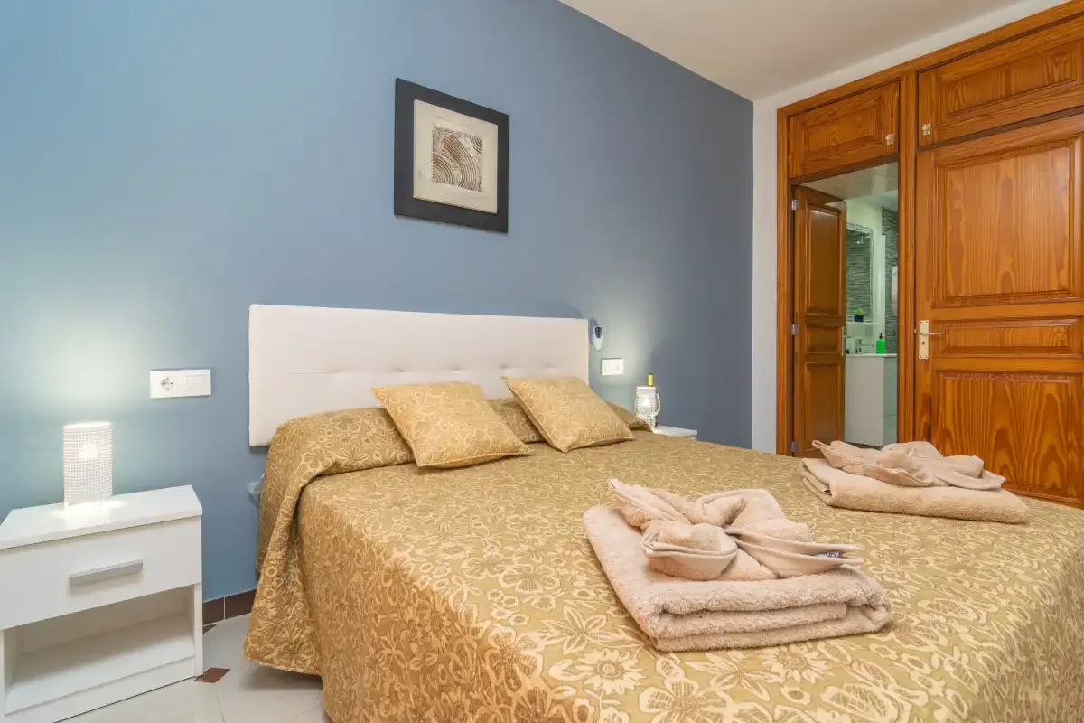 A bedroom with a double bed, bedside tables, and wooden wardrobes.