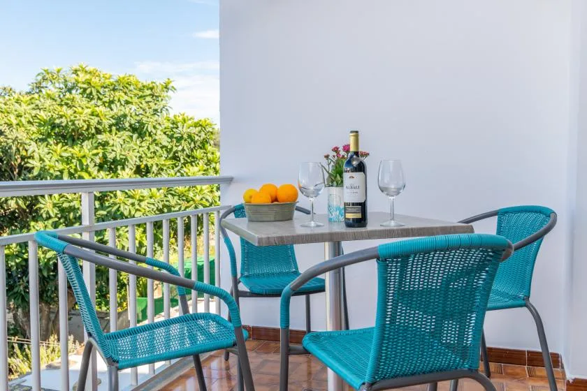 A balcony seating area has a small table with fruit and wine glasses.
