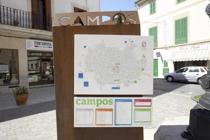 A large street map display stands in a sunny town square.