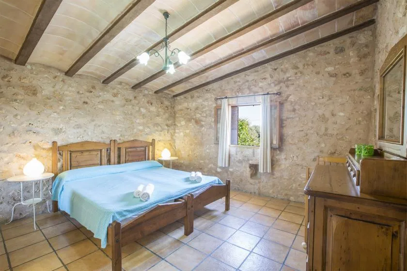 A rustic bedroom with a wooden bed and a small window.