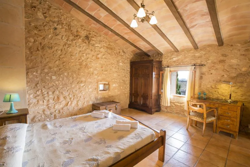 A rustic bedroom with a large bed and exposed ceiling beams.