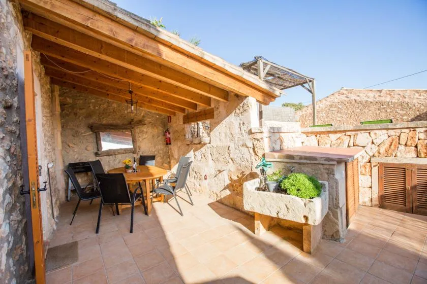 A covered stone patio with a dining table and built-in planter.
