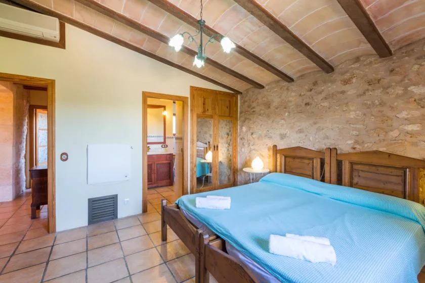 A bedroom with wooden beds, blue bedding, and exposed ceiling beams.