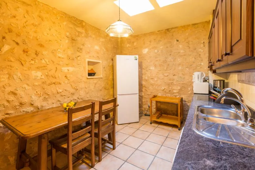 A rustic kitchen and dining area with a wooden table and refrigerator.
