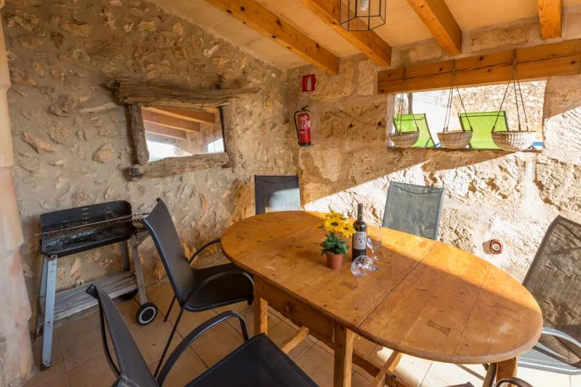 A rustic stone dining area with a wooden table and chairs.