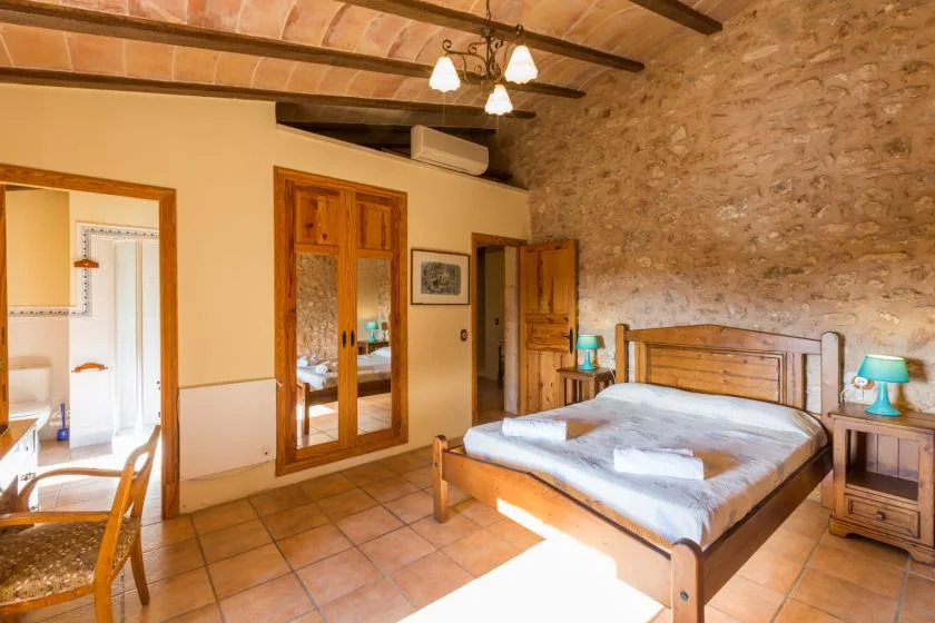 A rustic bedroom with a wooden bed beneath exposed ceiling beams.