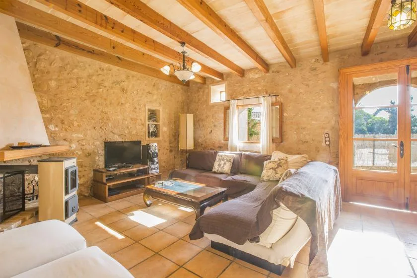 A living room with seating, a television, and exposed wooden ceiling beams.