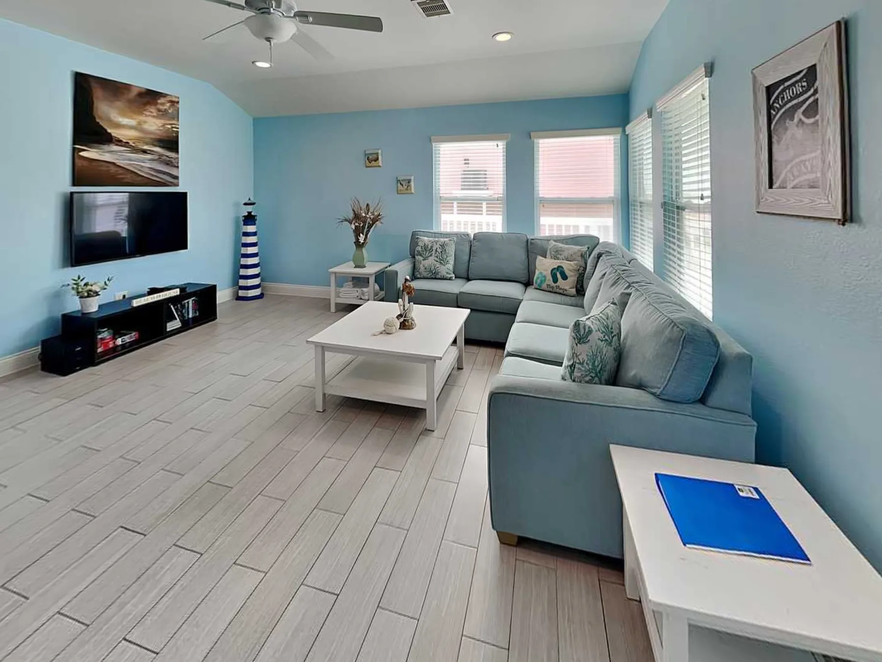 A bright living room with blue walls and an L-shaped sofa around a coffee table.