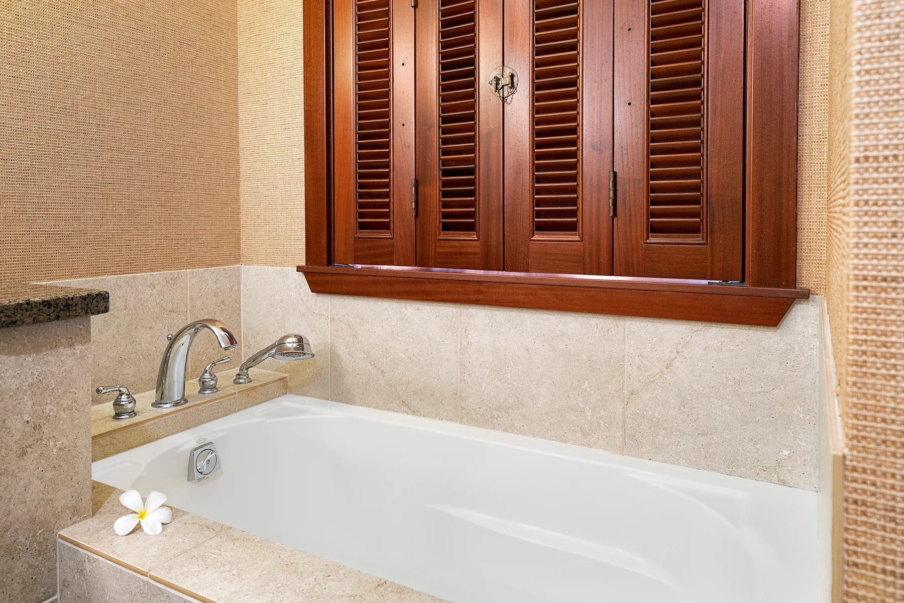Un baño con una bañera empotrada y contraventanas de madera.