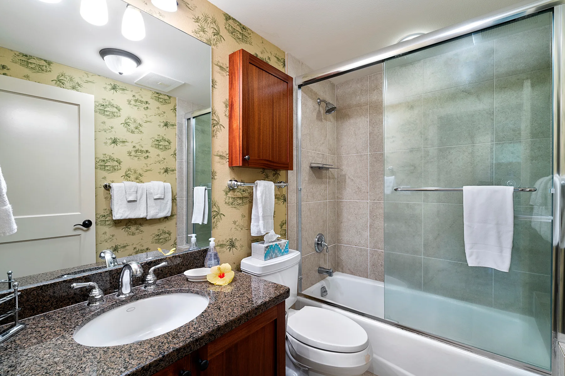 Un baño con lavabo y un espacio de ducha y bañera con paneles de vidrio.