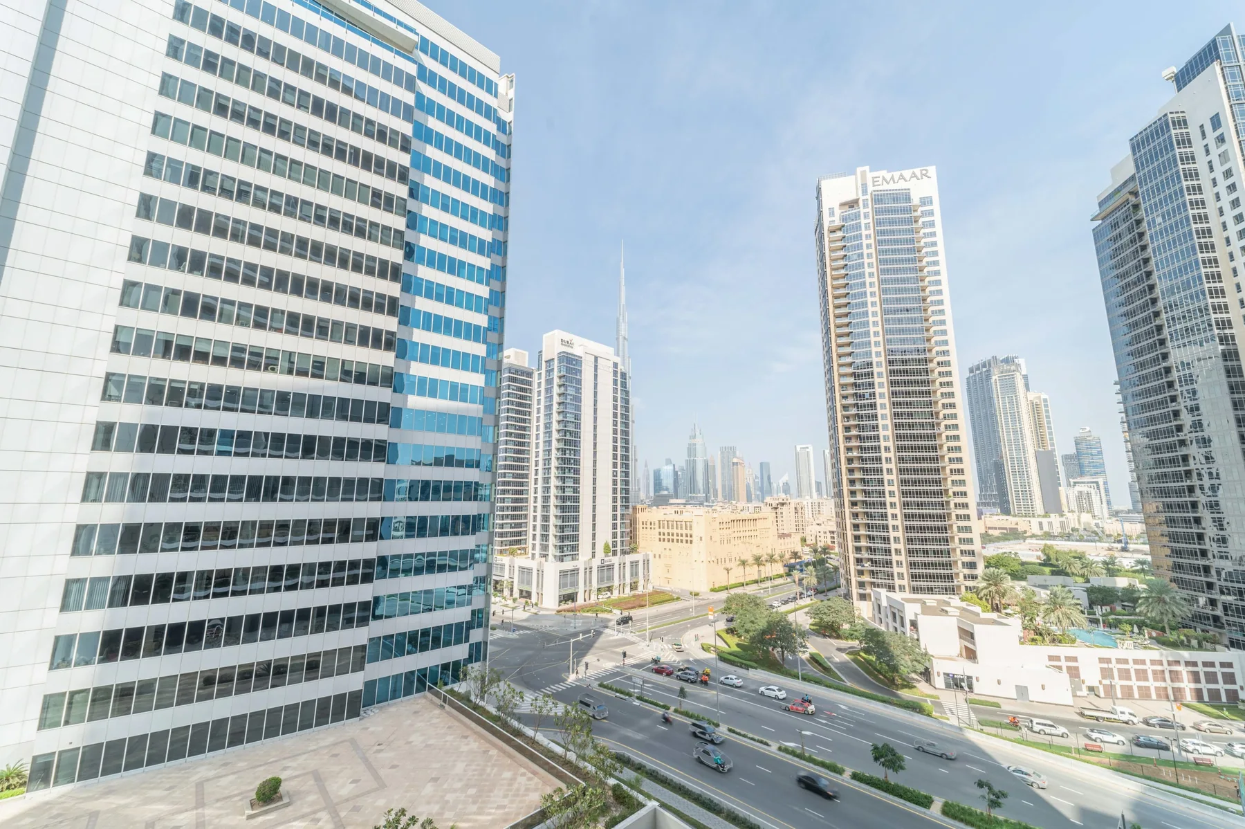 A city skyline of high-rise buildings overlooks a multi-lane road.