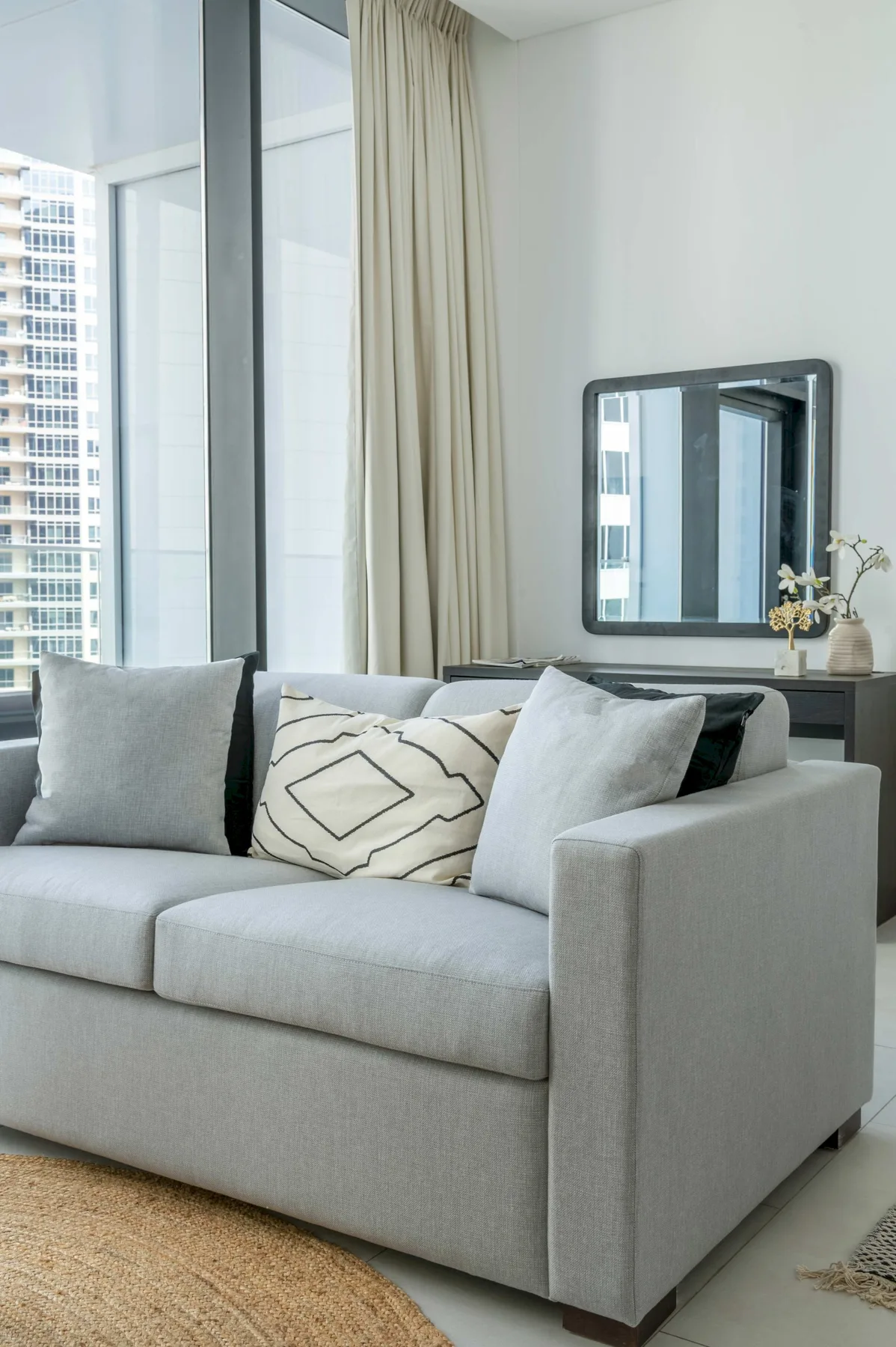 A living room with a light-colored sofa beside a large window.