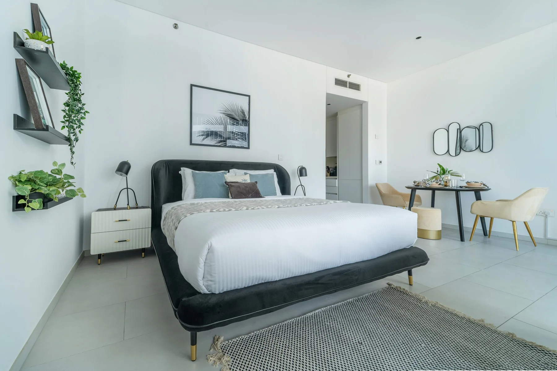 Un dormitorio luminoso con una cama arreglada y una pequeña zona de comedor.