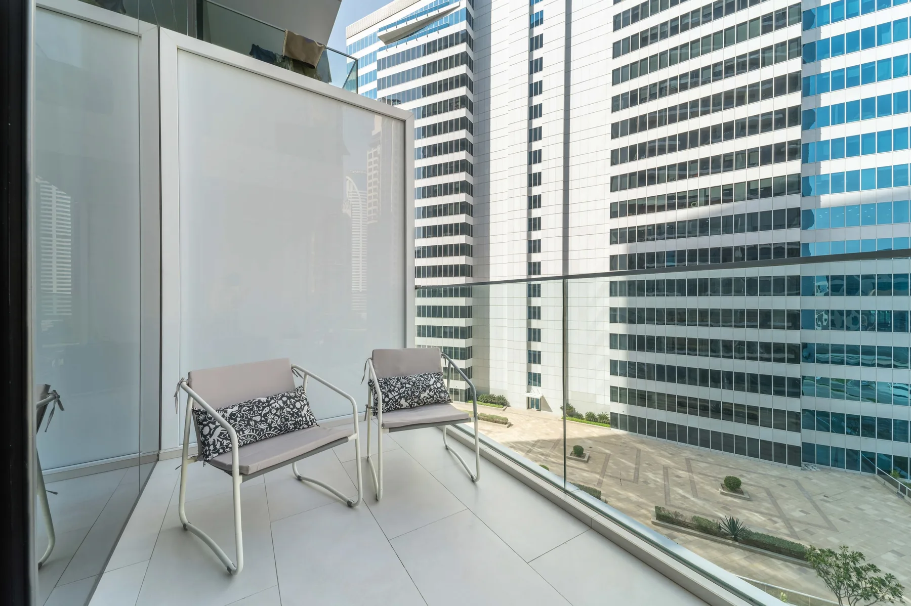 A balcony with two seats overlooks modern office buildings.