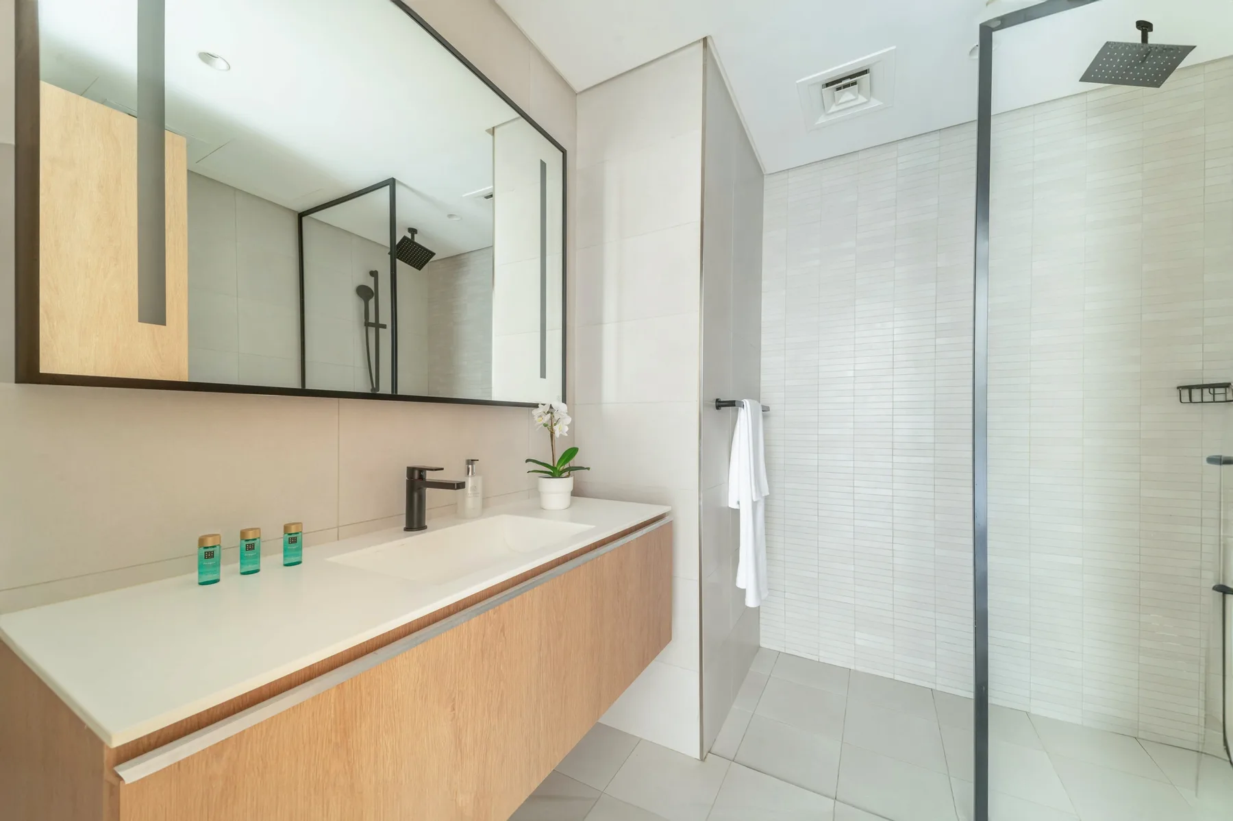 A modern bathroom with a long vanity and glass shower.