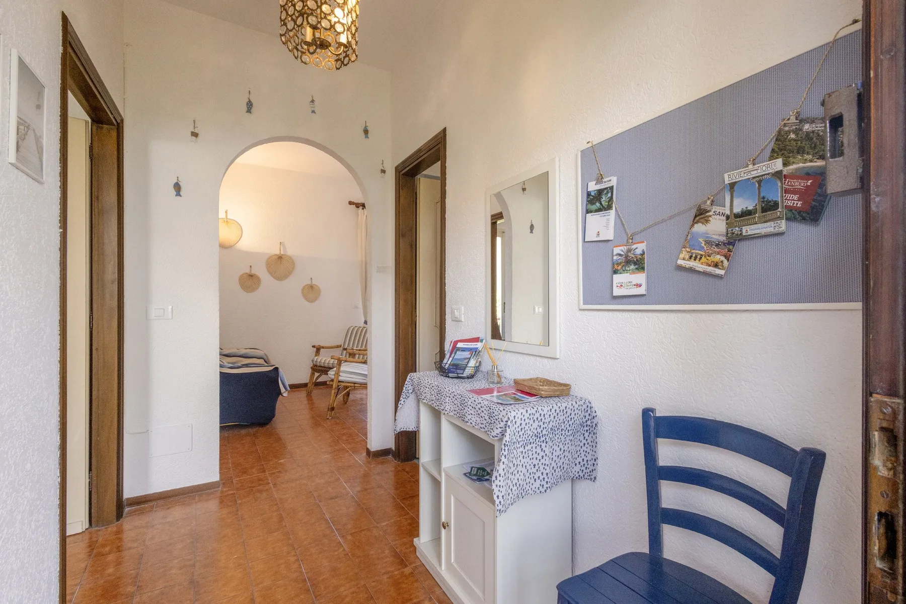 A bright hallway has an arched opening into a room with seating.