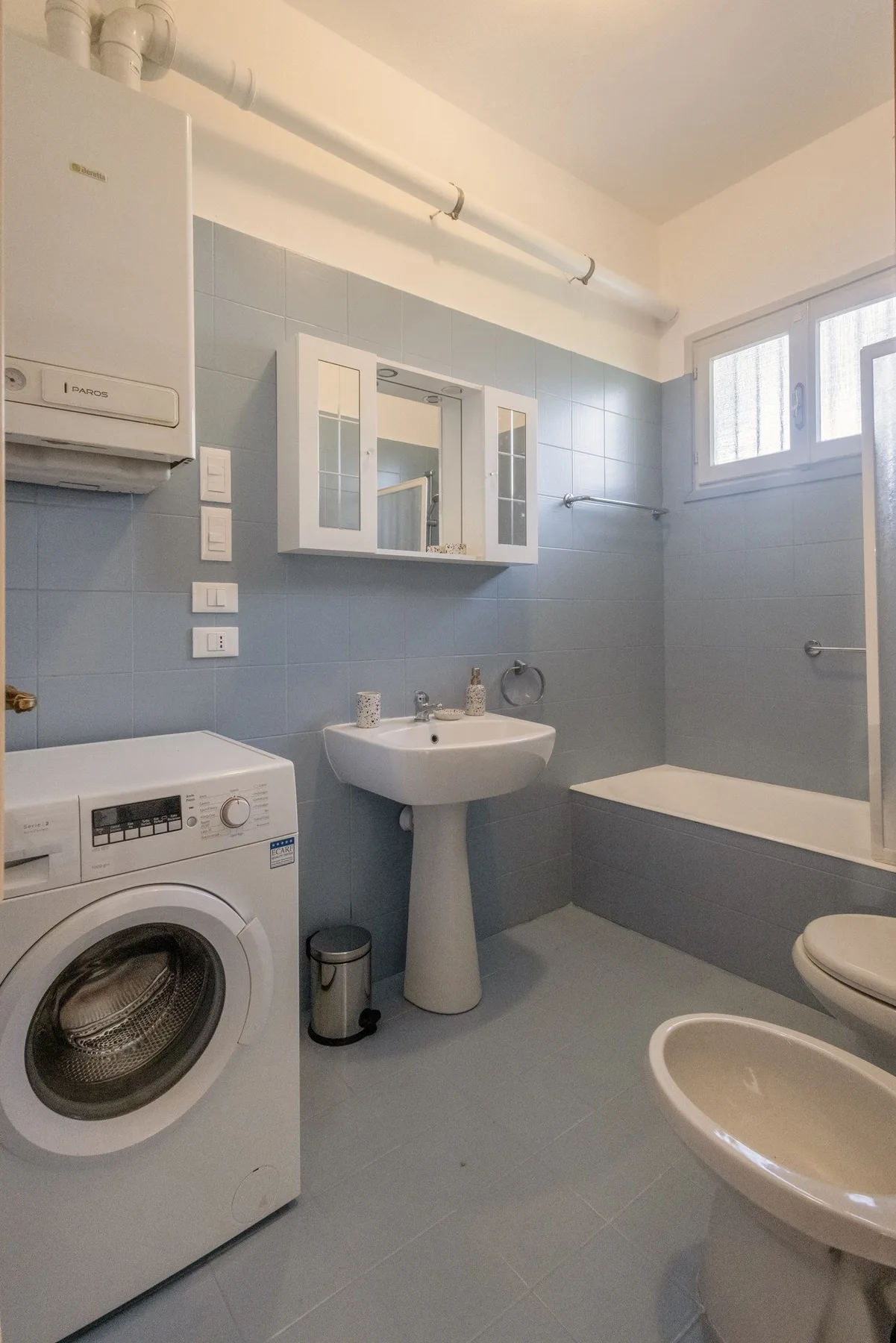 A bathroom with a sink, bathtub, and washing machine.
