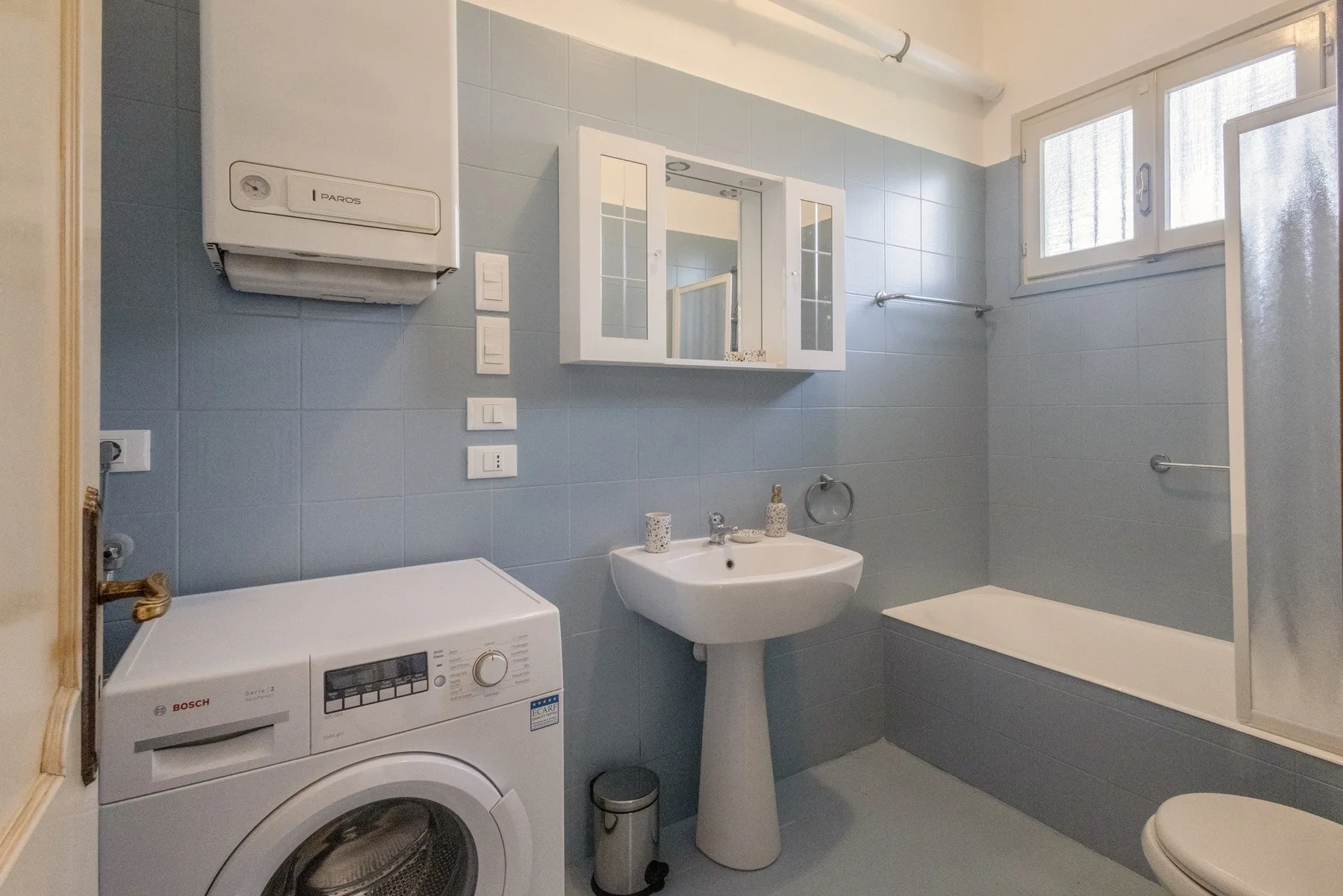 A tiled bathroom with a sink, bathtub, and washing machine.