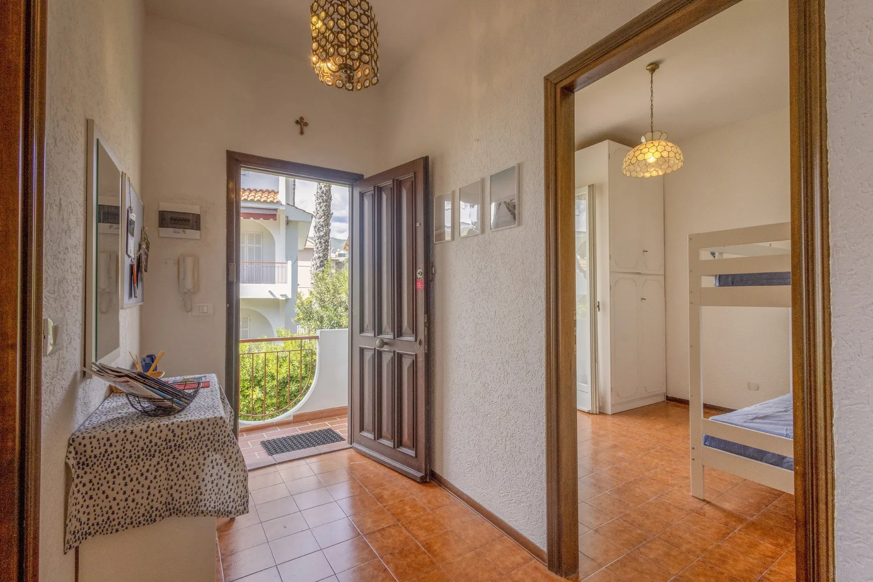 A tiled hallway opens onto a balcony, with a bedroom visible through a doorway.