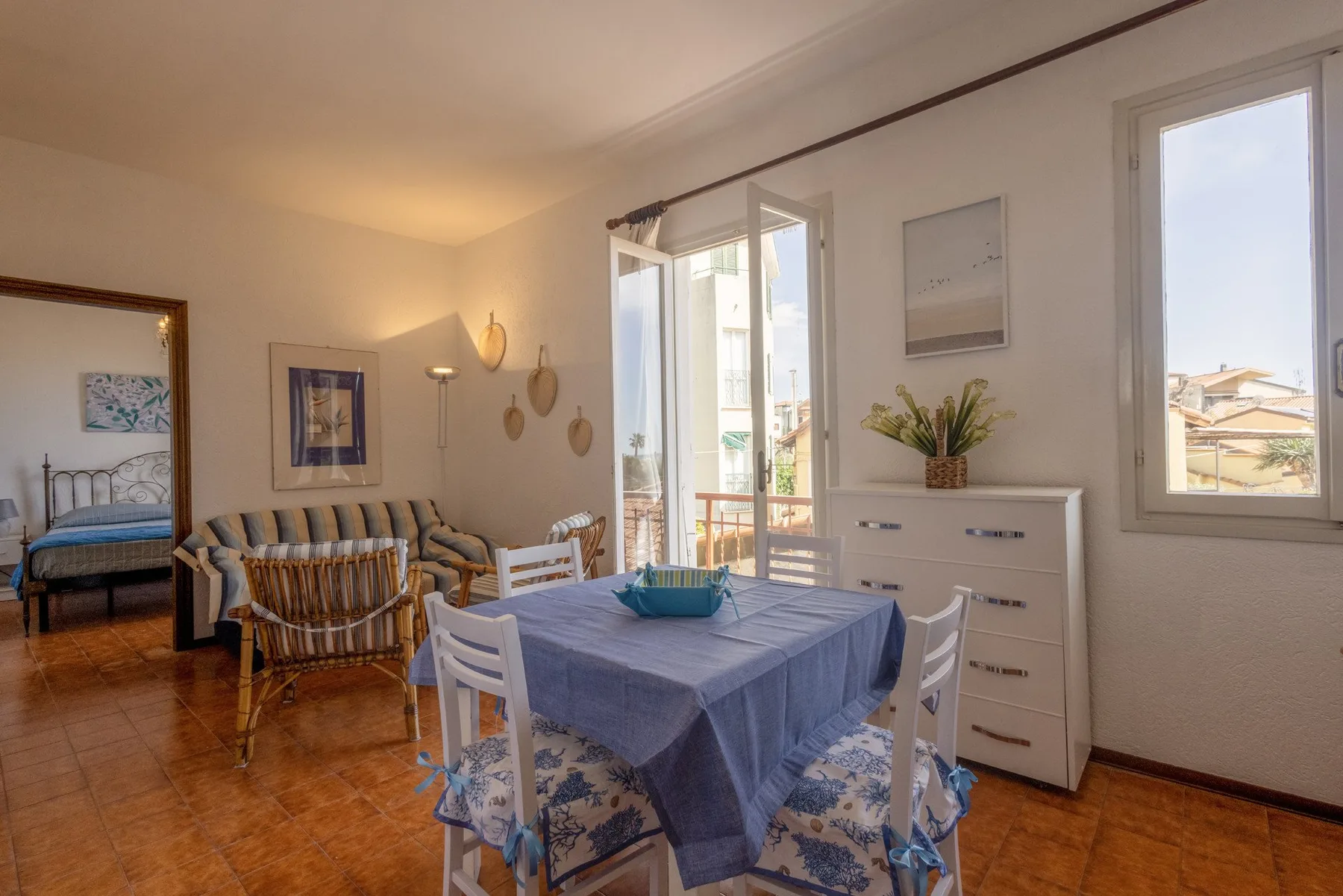 A bright dining area with a table set near the windows and living room seating.