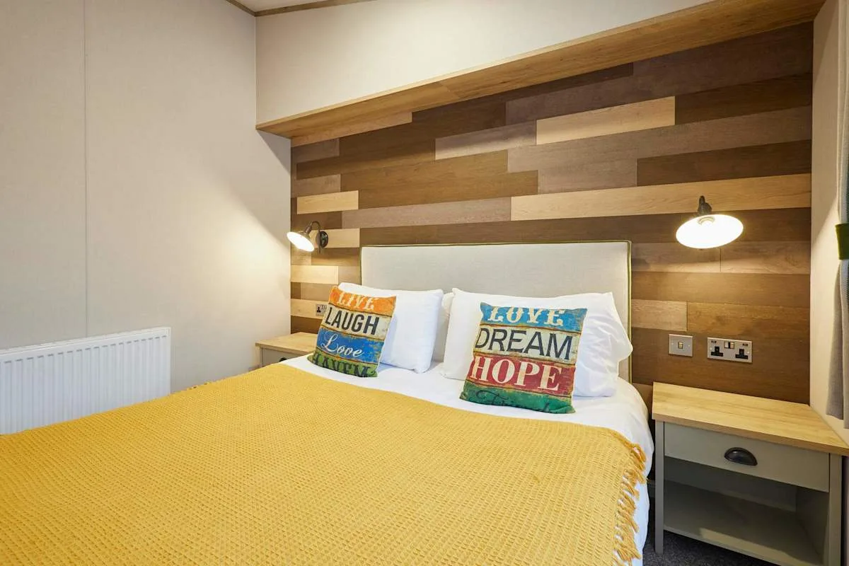 Un dormitorio con una cama doble, cojines coloridos y un cabecero de paneles de madera.